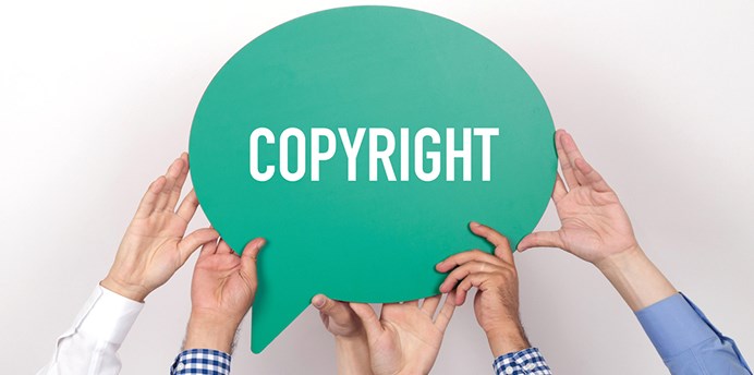 Hands hold up a sign in the shape of a speech bubble with the word "copyright" on the sign.