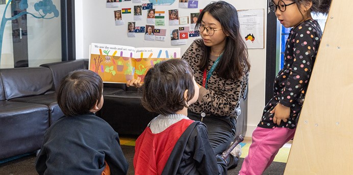 Educator at Barring Djinang kindergarten in South Melbourne reading to 3 children