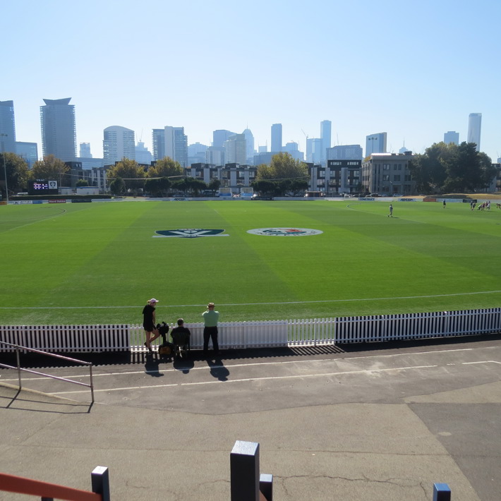 Green turf on North Port Oval with the city skyline in the background