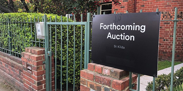 Forthcoming auction sign attached to fence of block of apartments in St Kilda