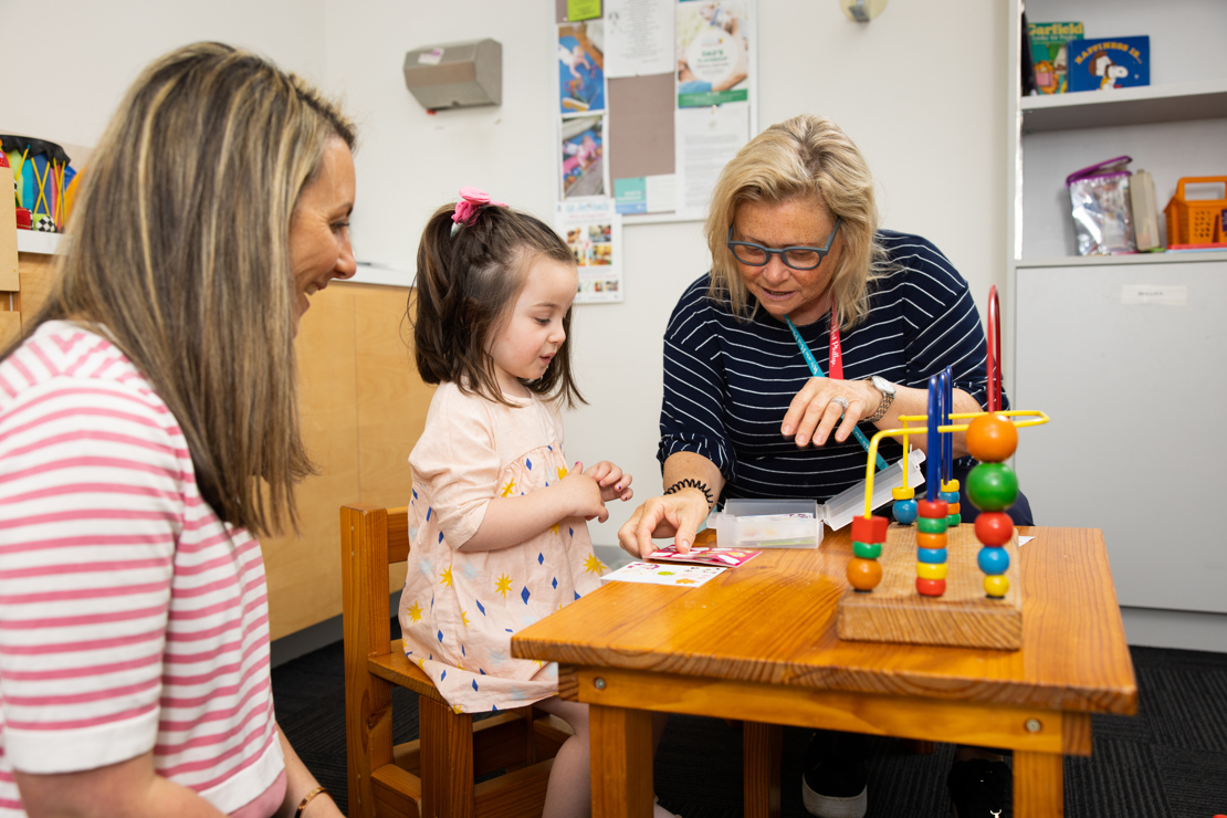 A small girl with her mother and a Council staff member looking at animal stickers