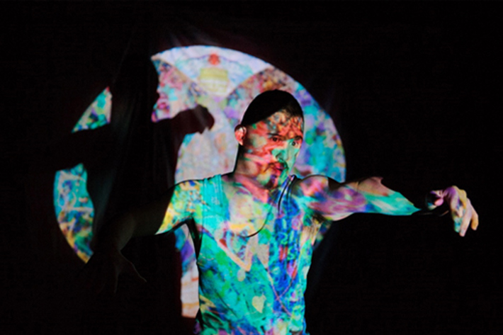a person standing with an outstretched arm in a pool of colourful light