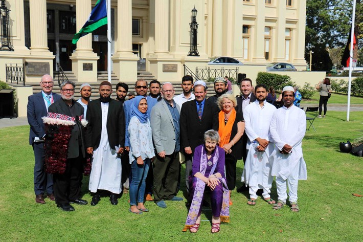 A group of people in religious clothing seated and standing in front of St Kilda Town Hall 