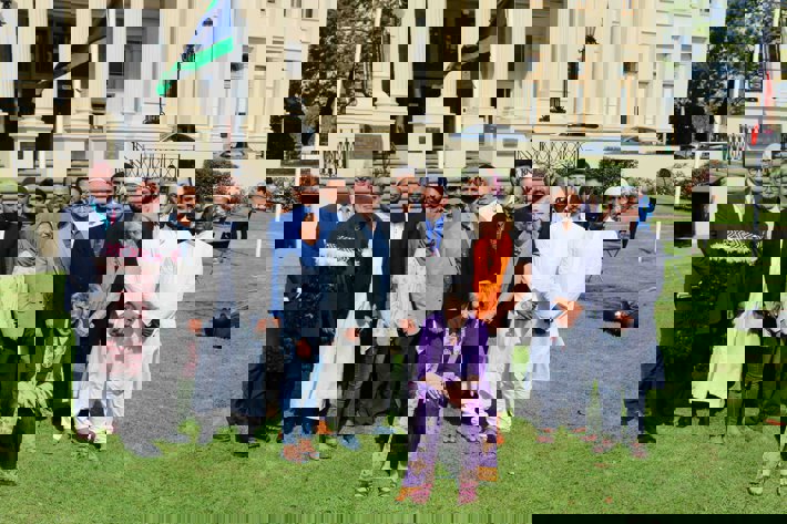 A group of people in religious clothing seated and standing in front of St Kilda Town Hall 