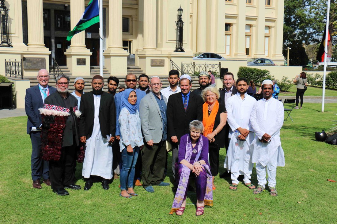 A group of people in religious clothing seated and standing in front of St Kilda Town Hall