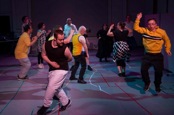 A group of people male and female dancing together in a room