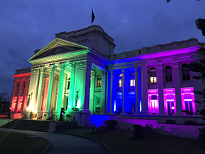St Kilda Town Hall lit up at night with rainbow floodlights to mark support for marriage equality