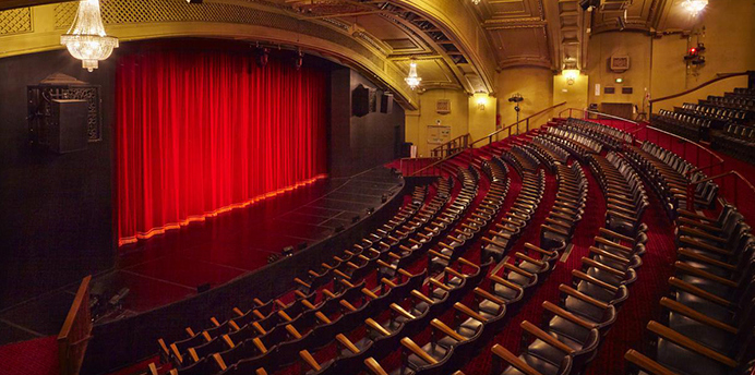 Interior view of the National Theatre in St Kilda showing the stage, red curtain and tiered seating.