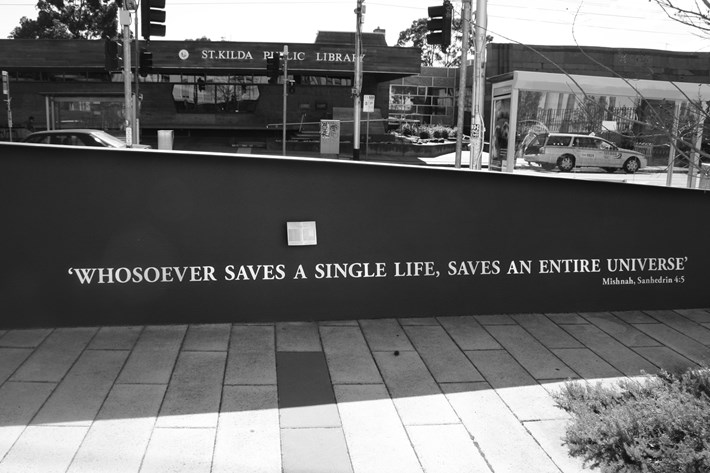 The memorial wall with statement inscribed in silver polished steel against a black wall "Whosoever saves a single life, saves an entire universe".