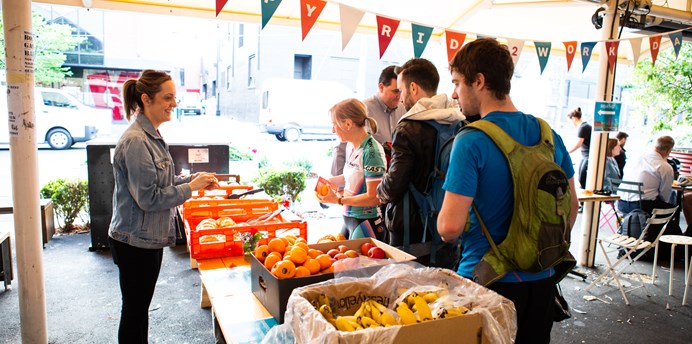 People lining up to collect fruit from a pop-up stall