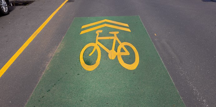 Green painted bike lane on a road with a bright bike image and arrows pointing forward