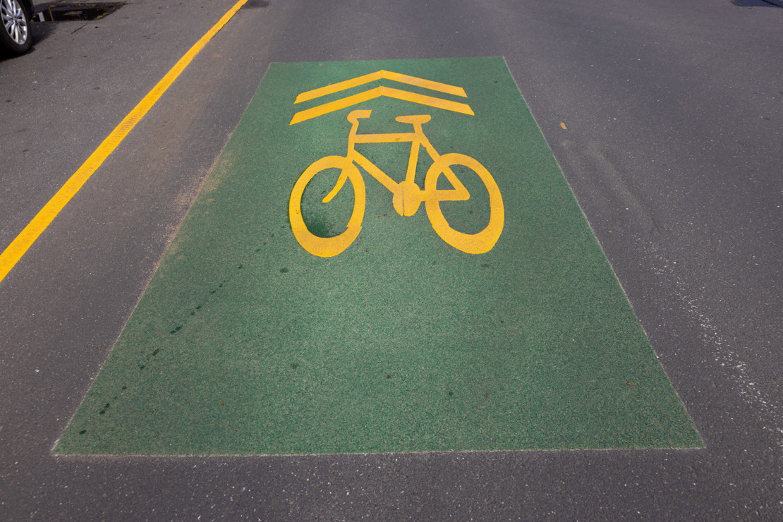 Green painted bike lane on a road with a bright bike image and arrows pointing forward
