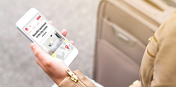 A woman holding a smartphone looking at listings for short-stay accommodation