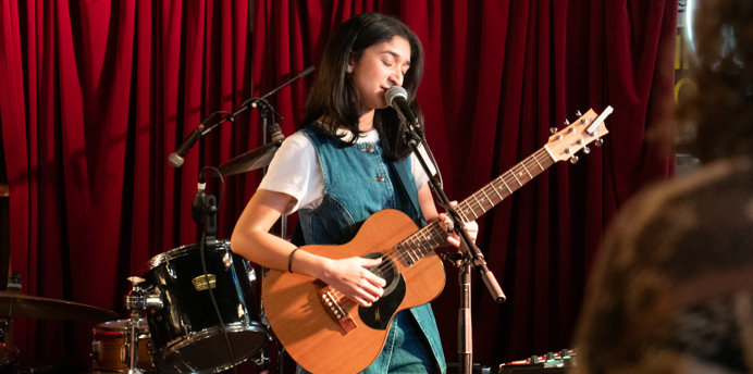 Young musician playing her guitar and singing on stage at The Espy, St Kilda