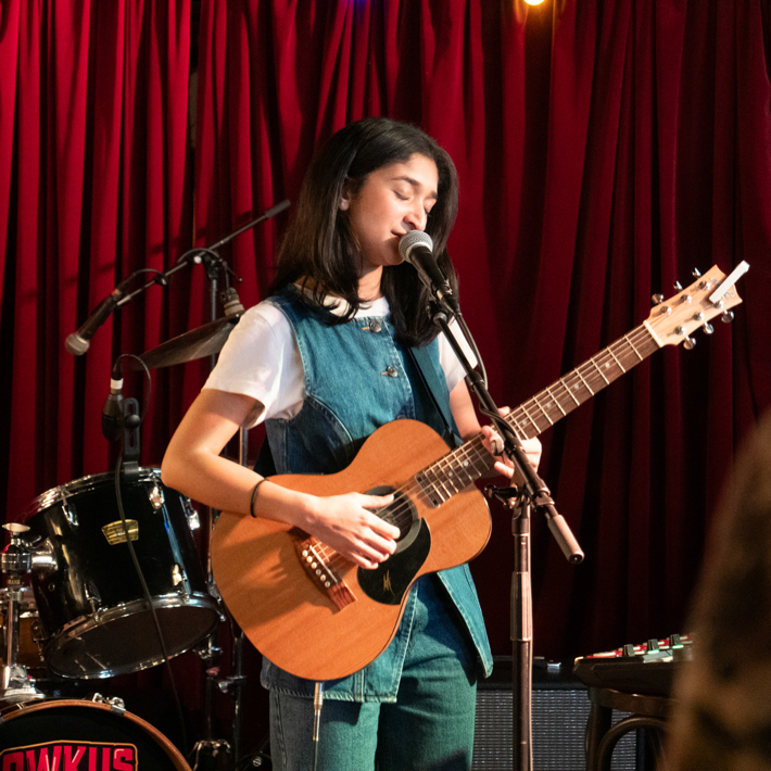 Young musician playing her guitar and singing on stage at The Espy, St Kilda