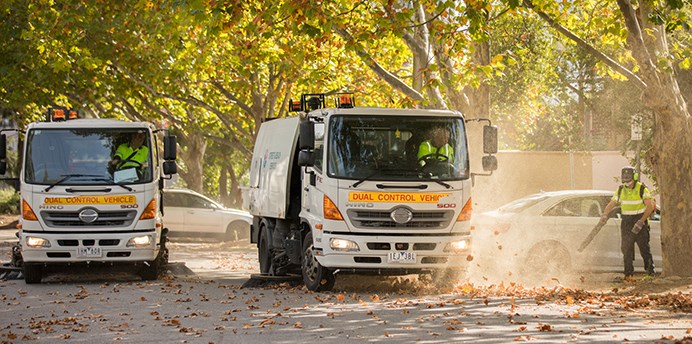 Council street cleaning team removing leaves from suburban street