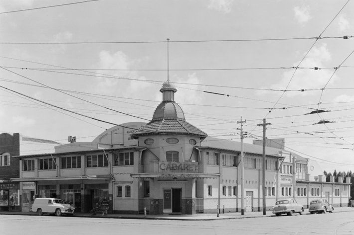 Old two story building standing on a corner block, notable feature and small central dome that rises up against the skyline