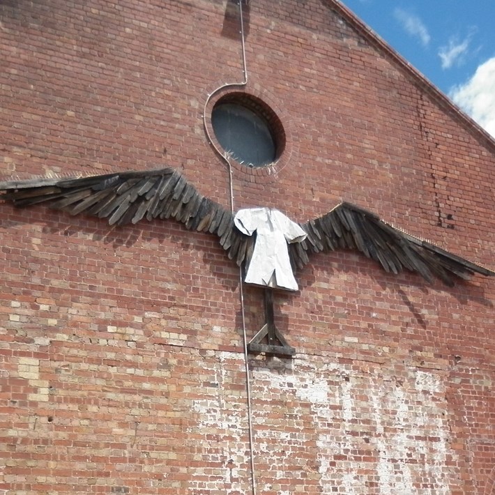 Sculpture of a white dress with wings on the outside wall of the Gasworks Arts Park Theatre