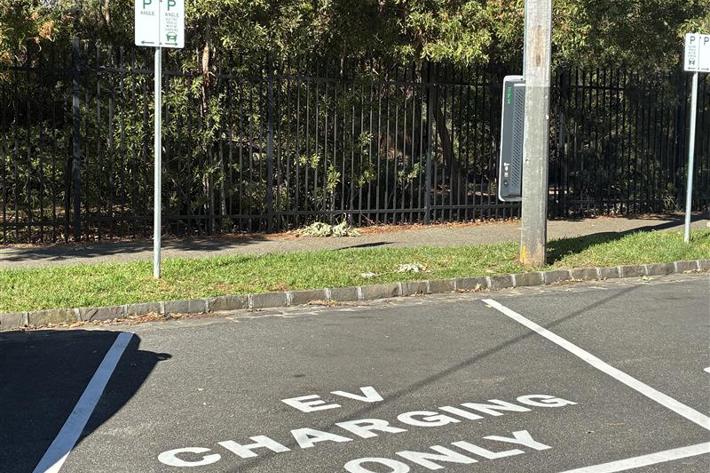 A photo of a pole-mounted electric vehicle charger and dedicated parking space.